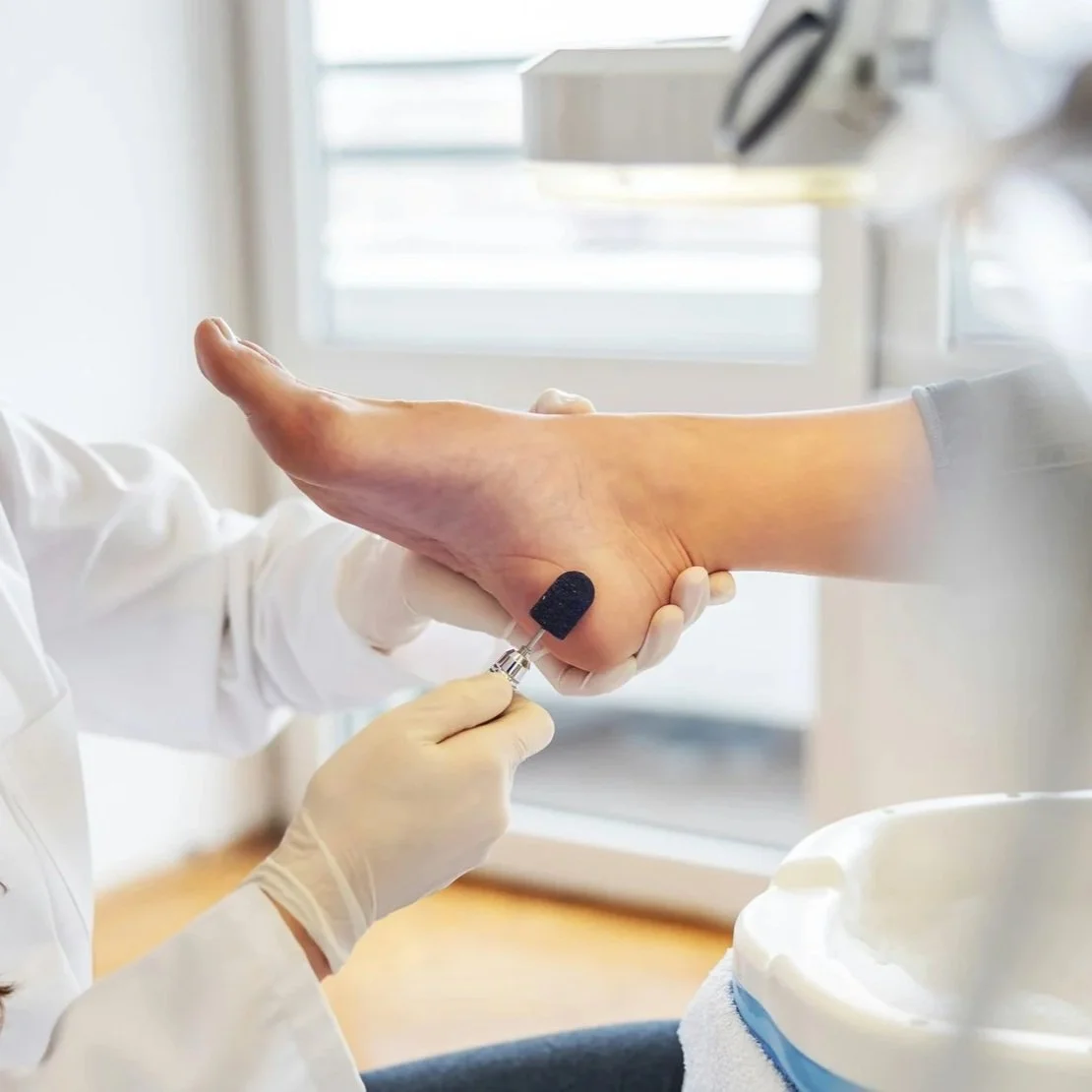 A nail technician gently exfoliating the skin on a woman's heel.