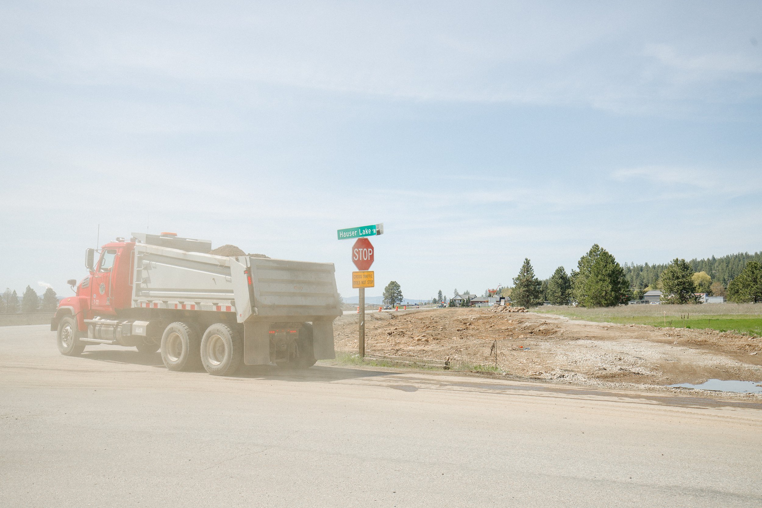 A truck carrying dirt passes by a construction site on Hauser Lake Rd