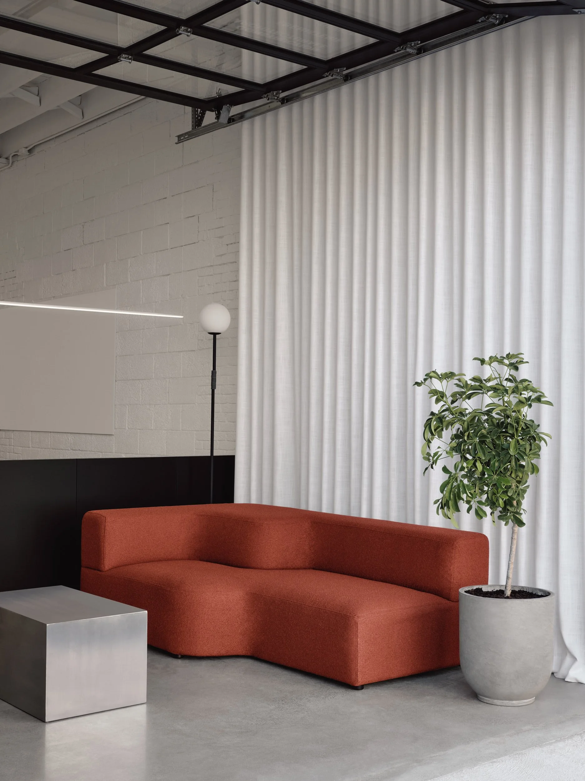 Salon moderne avec un canapé orange, une plante en pot et un lampadaire à palette, avec un rideau blanc et un plafond en verre.