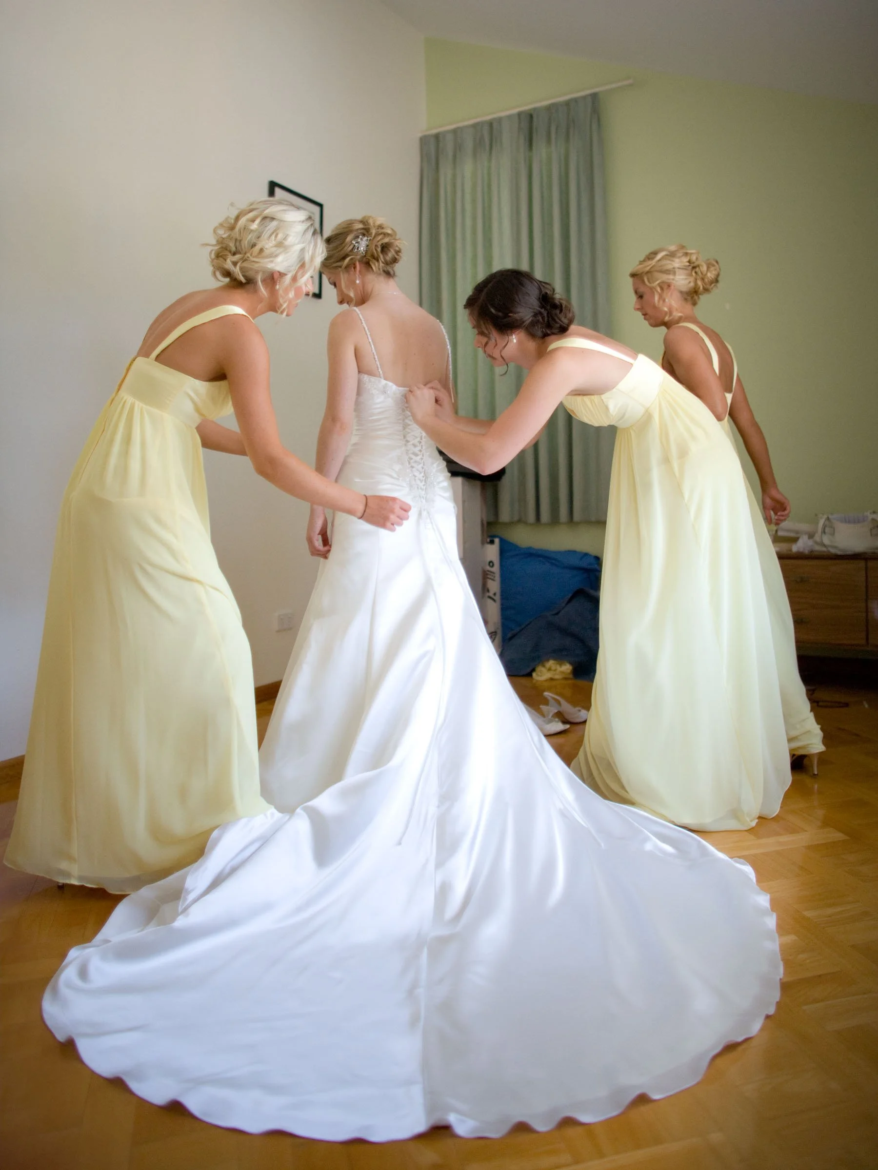 Bride Naomi being assisted by her bridesmaids with her dress at her final preparations