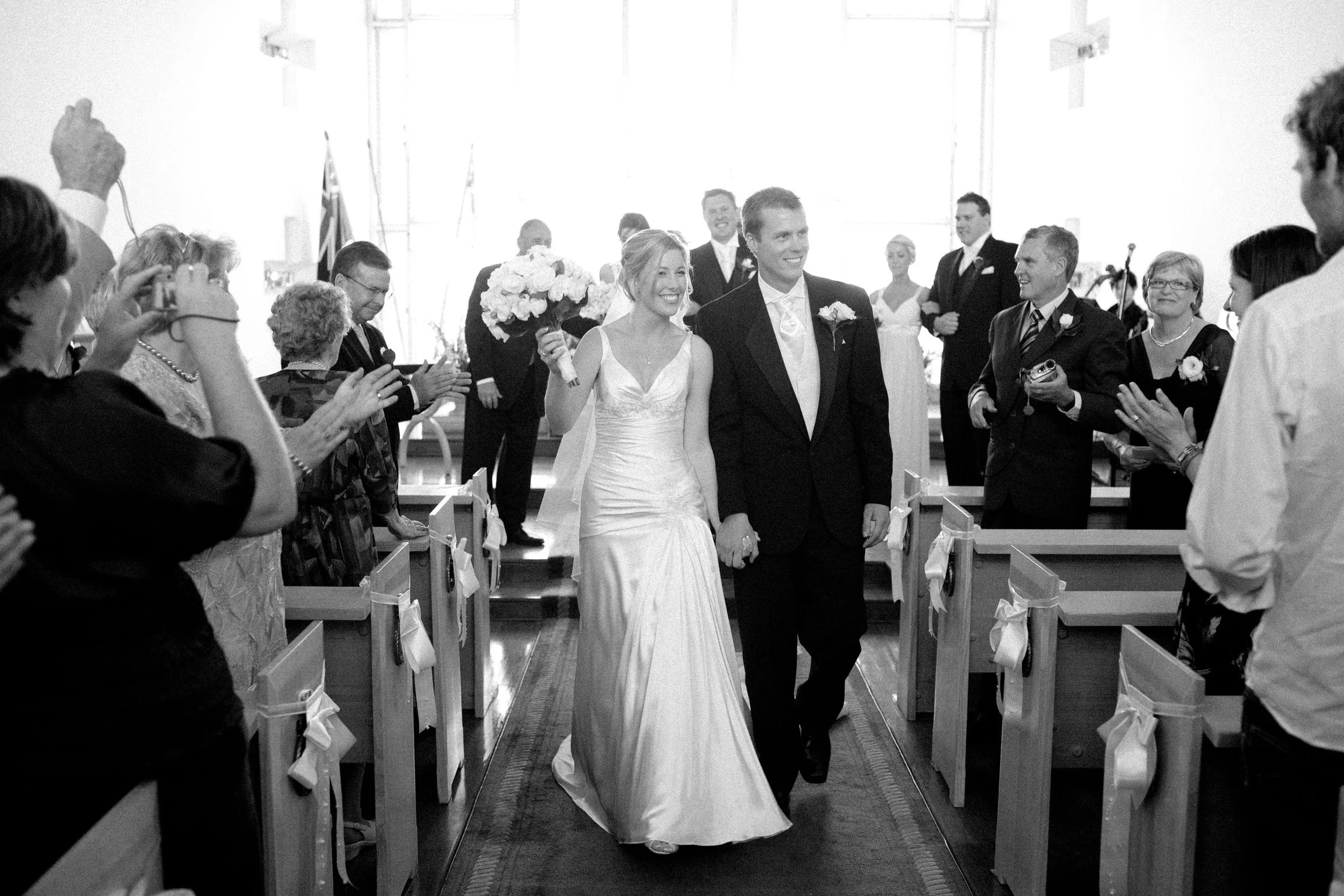 Naomi and Justin leaving HMAS Watson Chapel after their Sydney wedding ceremony in black and white