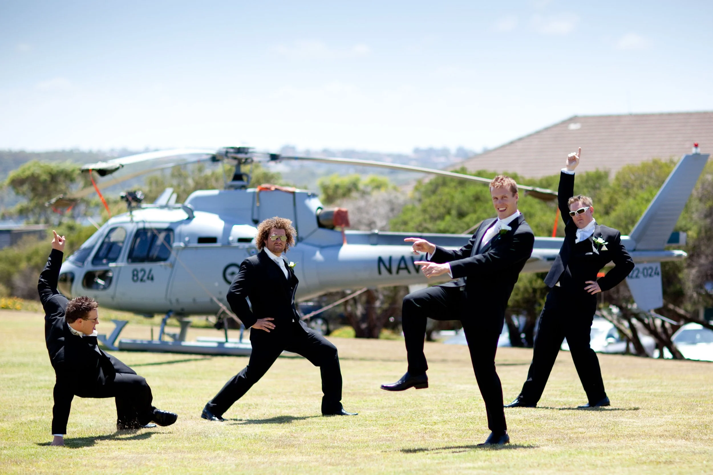 Groom Justin posing with his groomsmen in front of the Navy helicopter at HMAS Watson Chapel.