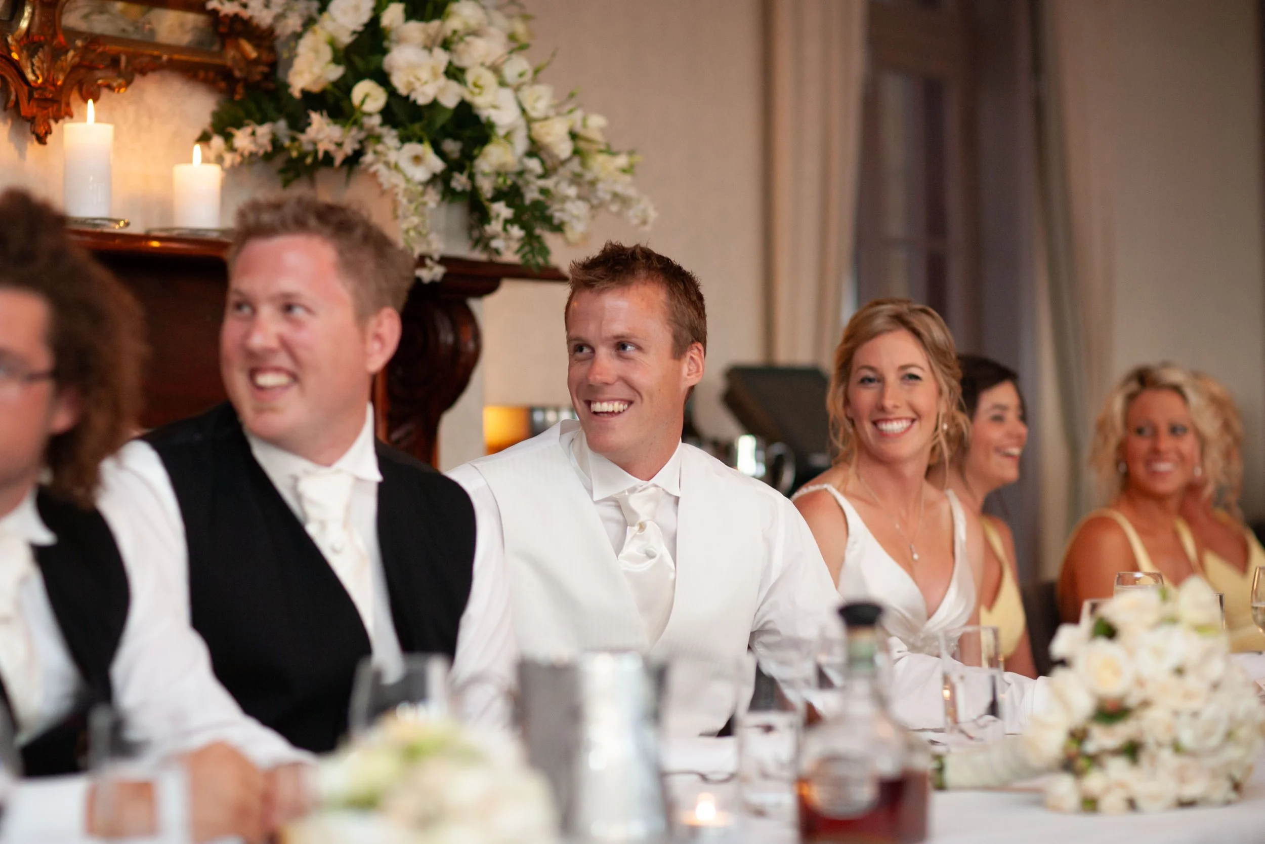 Smiling bridal party during speeches at the Gunners’ Barracks reception of Naomi and Justin