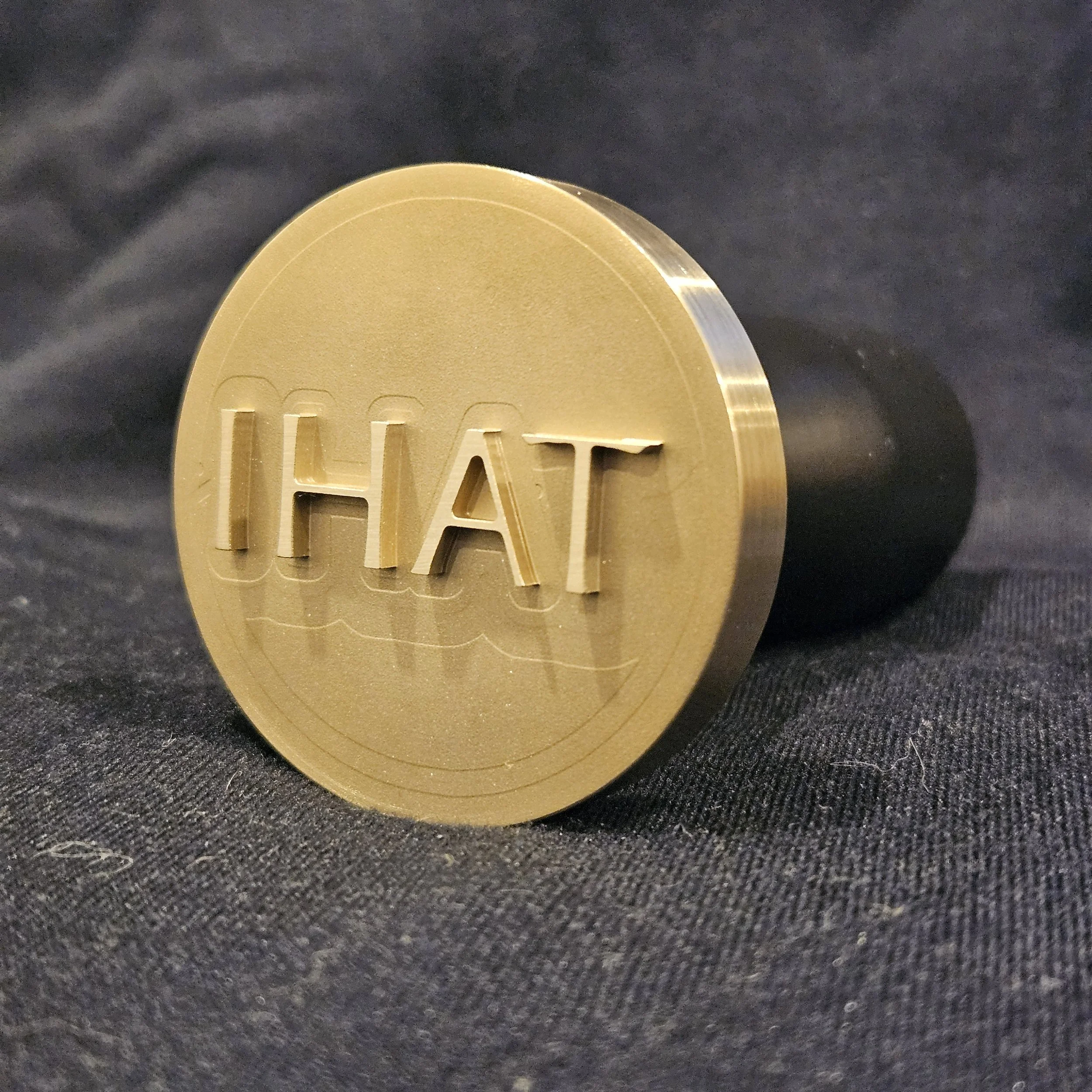 A gold-colored coin with the word 'CHAT' engraved on it, resting on a dark fabric surface.