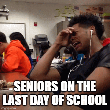 A student in a classroom visibly distressed, holding his head with one hand while wearing earphones, with other students in the background. Text overlay reads 'Seniors on the last day of school.'