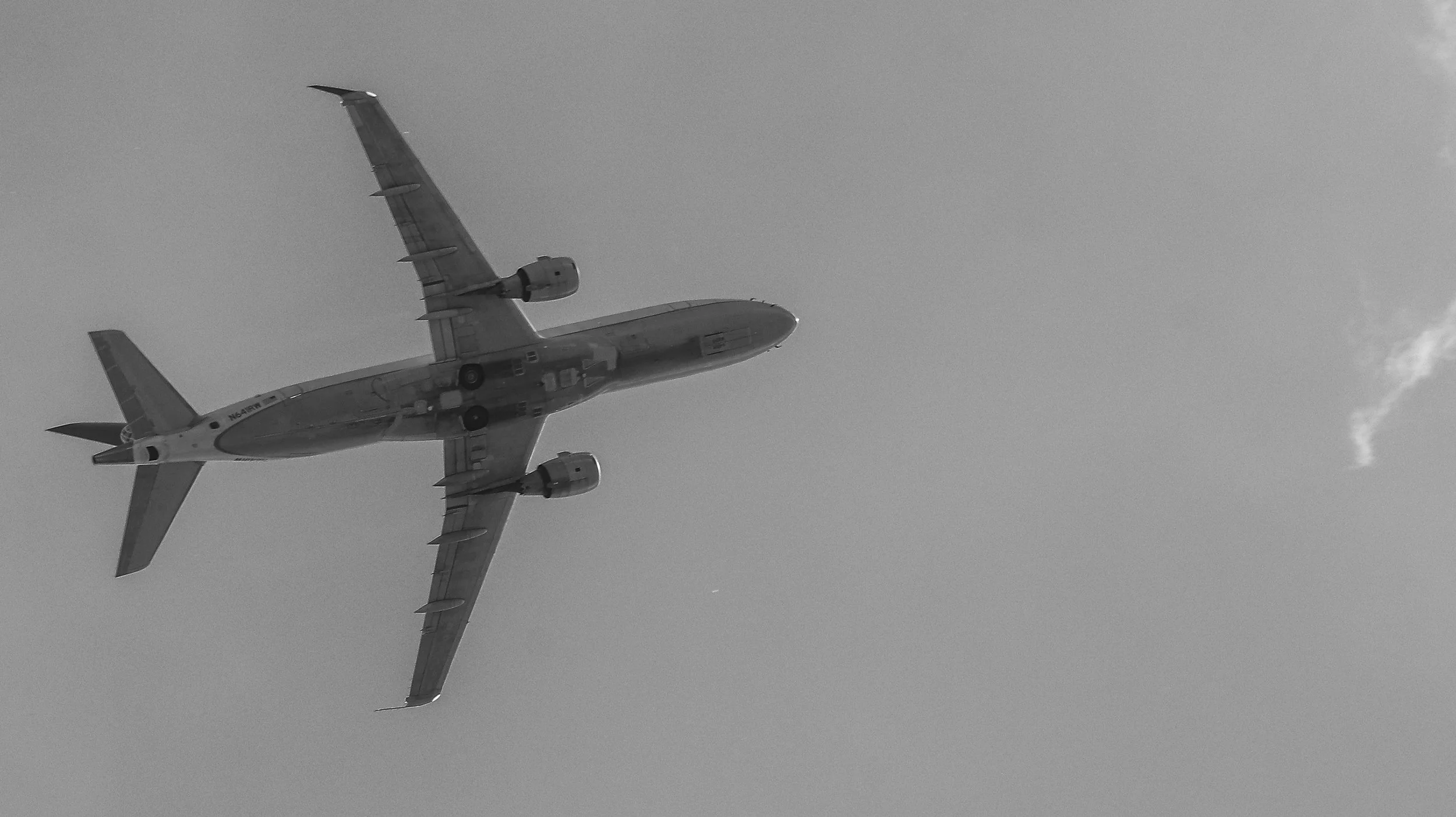 Aerial view of a commercial airplane flying in the sky, seen from underneath.
