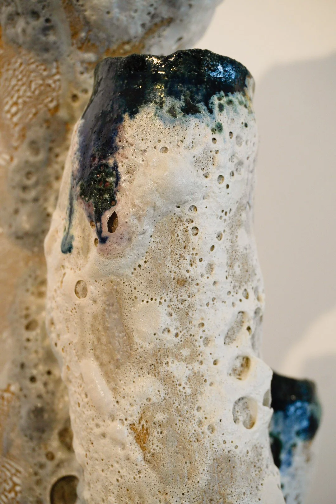 Close-up of a textured, weathered, foam-covered object with patches of black and blue paint.