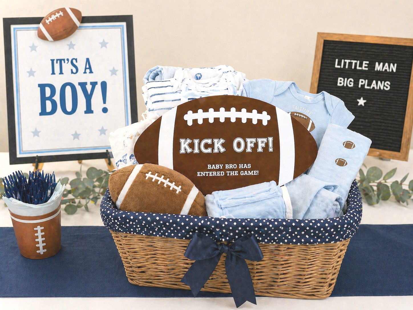 A brown acrylic laser cut sign amongst other gifts for a baby shower. The baby boy party has a football theme and blue color scheme.