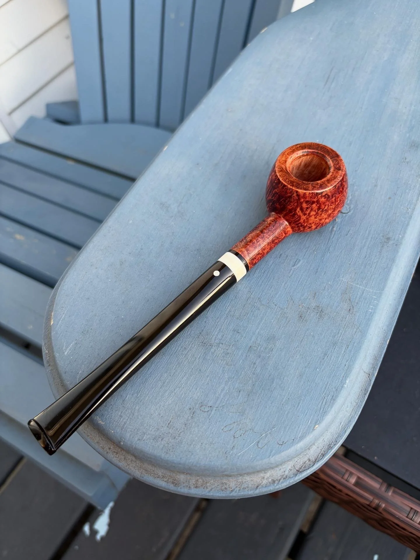 A prince smoking pipe with a wooden bowl and black stem resting on a blue wooden bench.