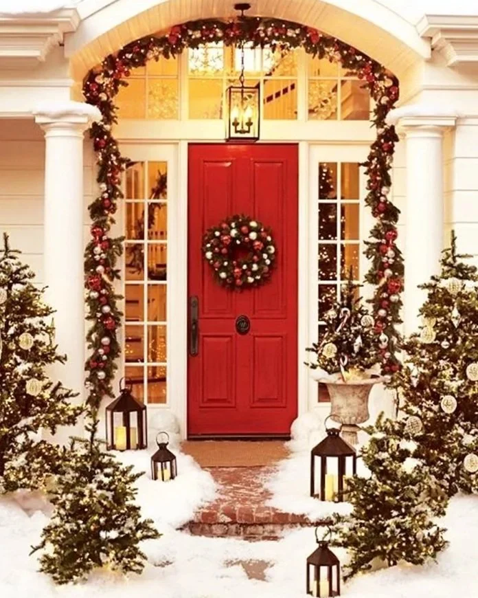 BeautifulWinterNuanceEntranceTraditionalChristmasFrontDoorDecorationsWithSnowandLovelyChristmasTreesandLanternWithRedDoorandGlassWindowsBeside.jpg