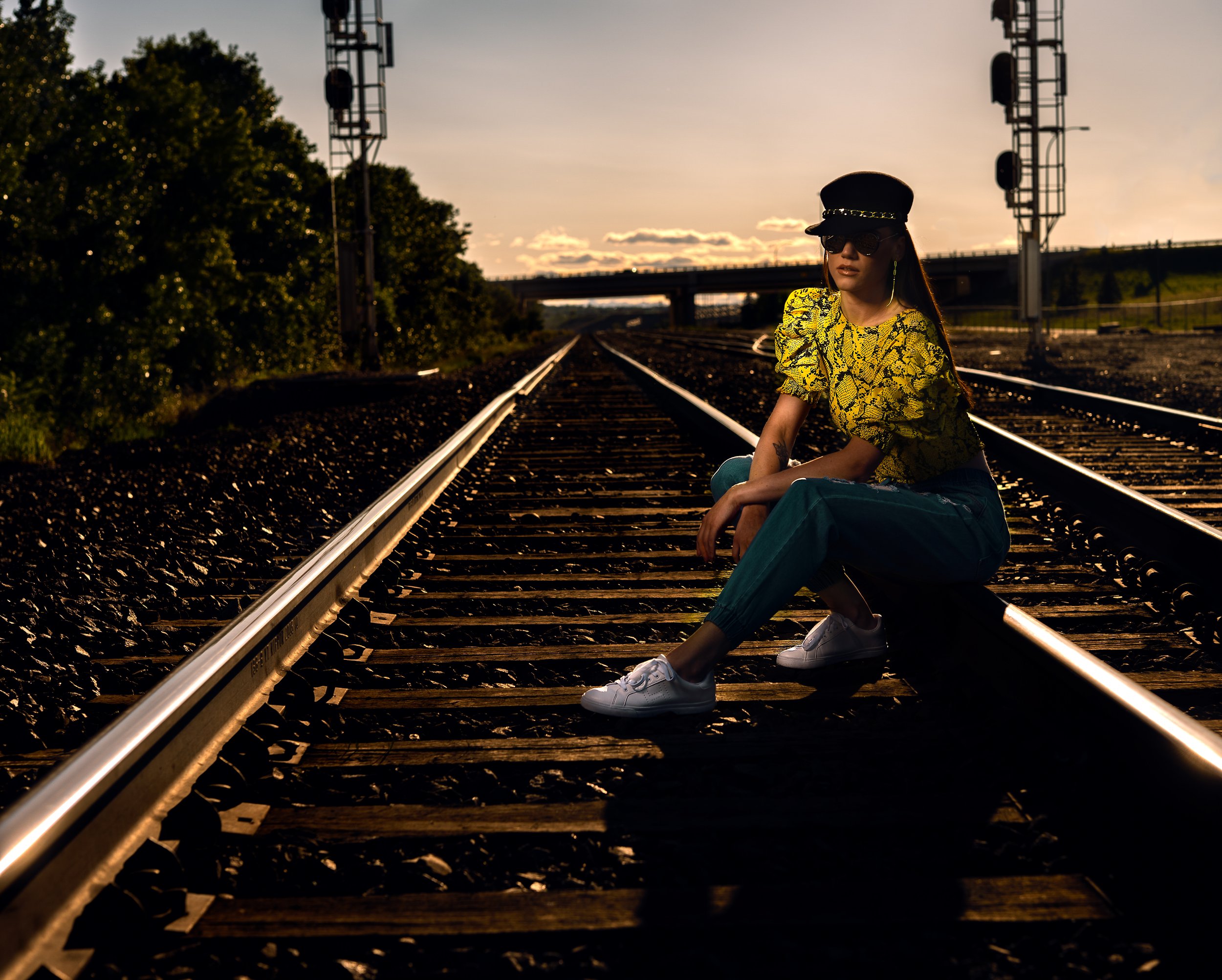 cinematic editorial portrait on railway tracks at golden hour – Calgary fashion photography