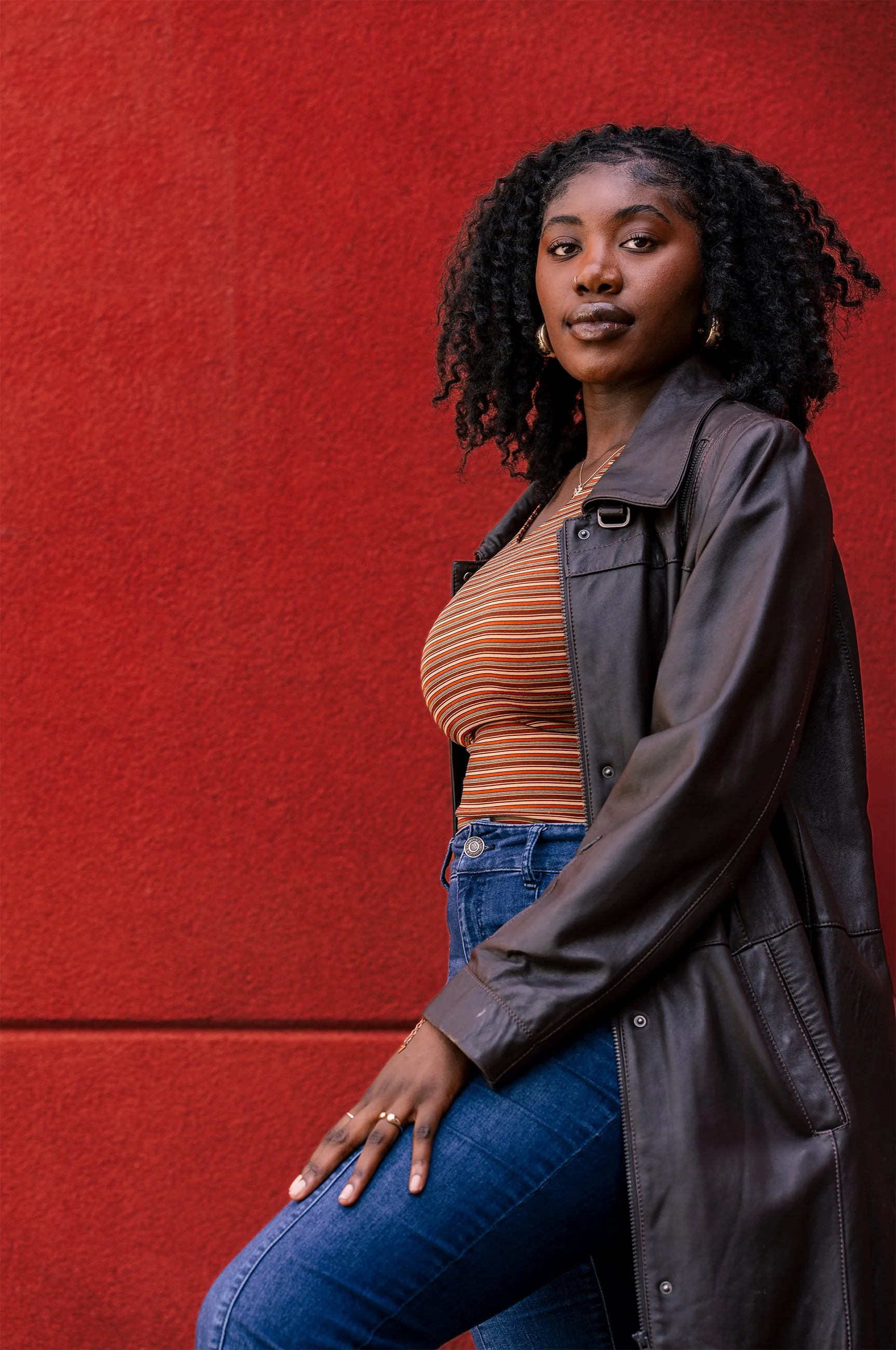 editorial outdoor portrait of woman against textured red wall – Calgary fashion photography