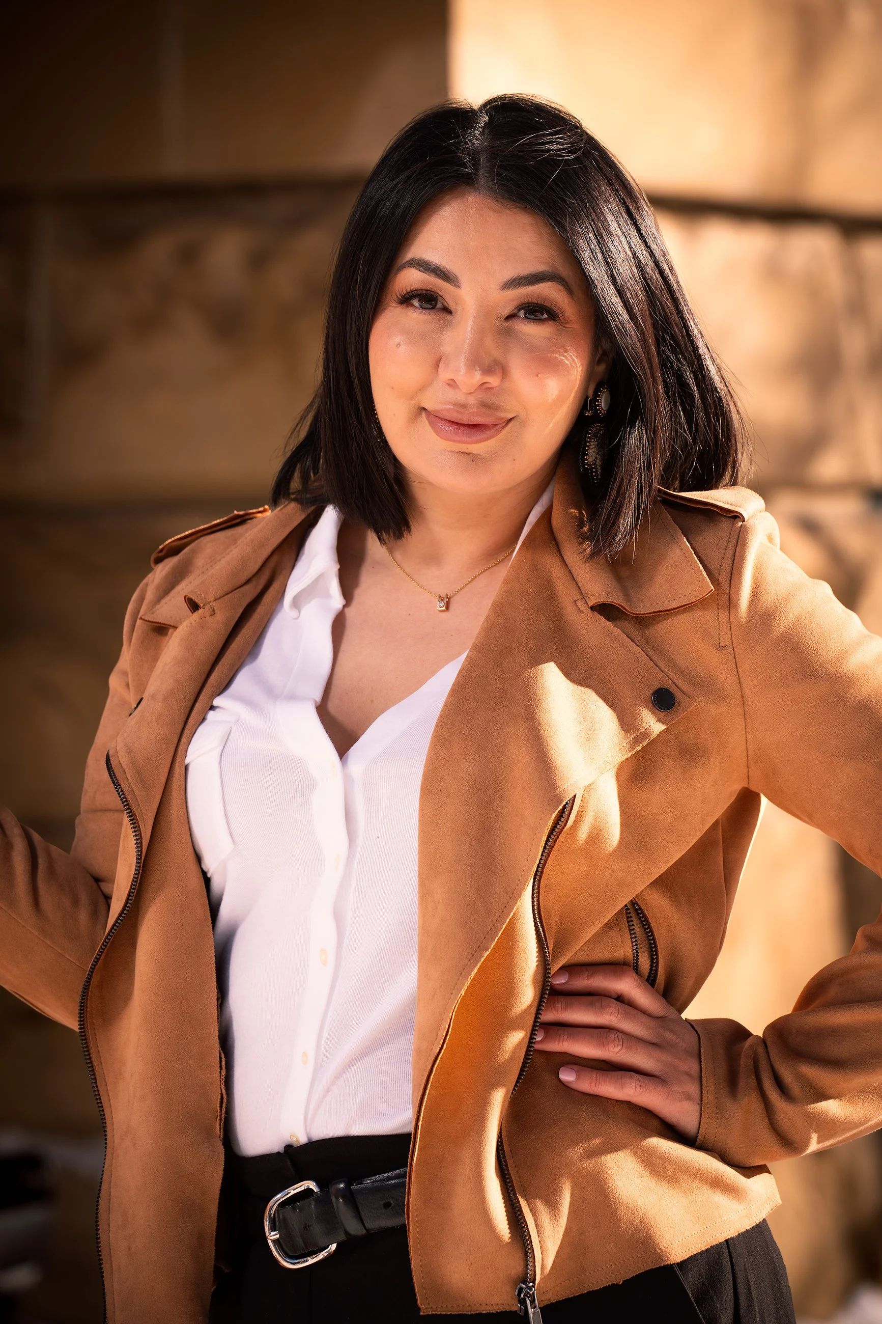 Golden hour portrait of a woman in a tan jacket, with warm directional light shaping her face and creating soft shadows.