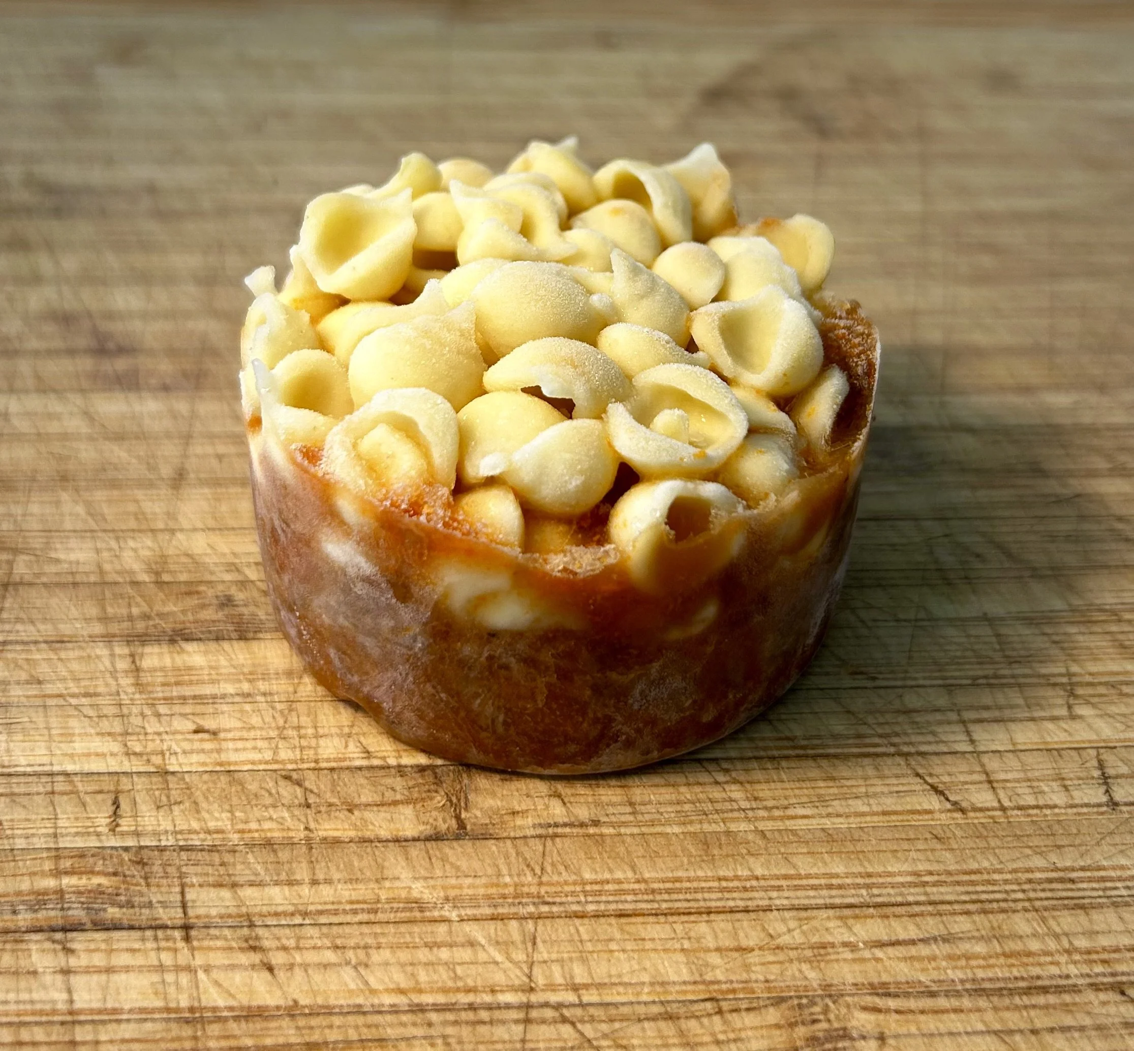 A mini childs portion of pasta Bolognese sitting on a wooden cutting board.