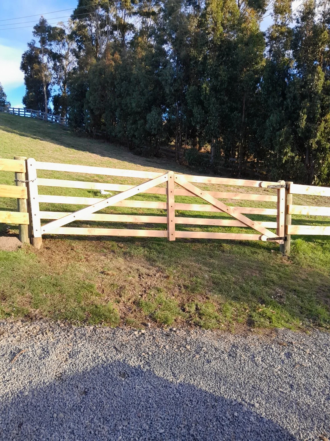 Wooden gate in front of grassy area and trees in the background.