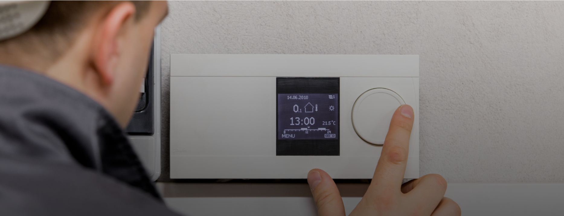 Person adjusting digital thermostat controlling home heating system