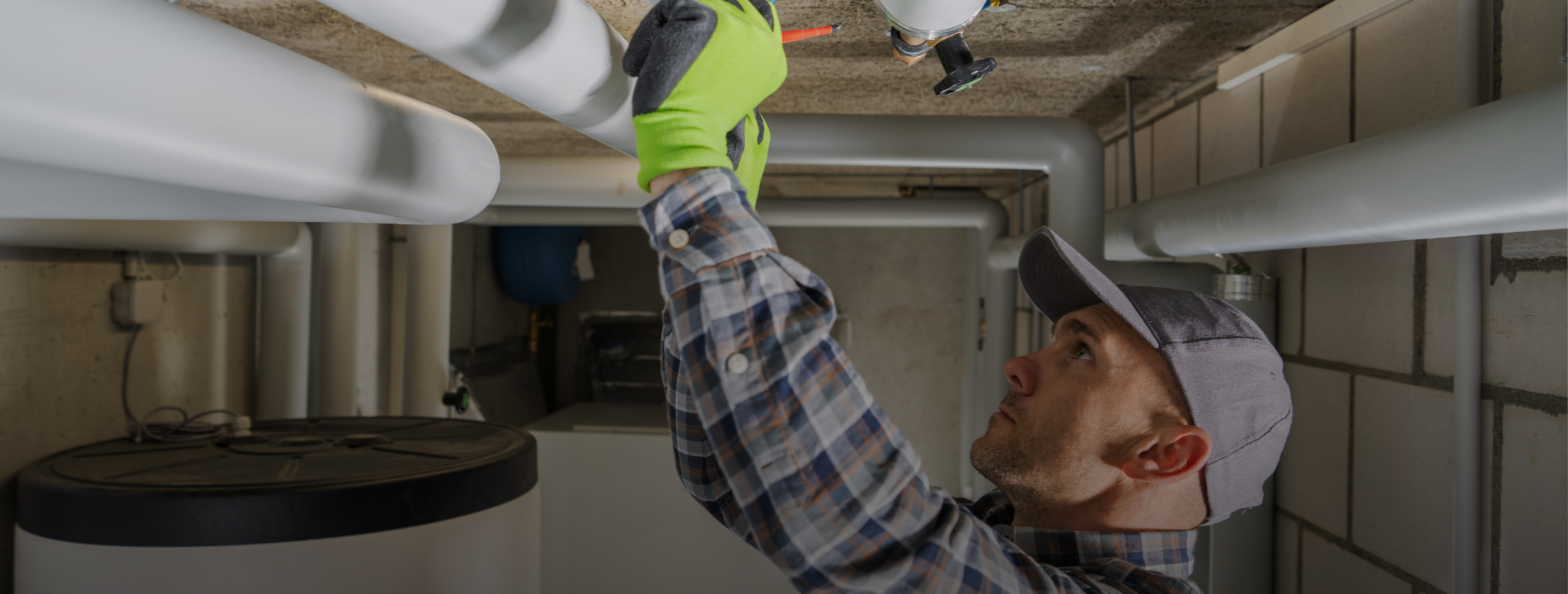 Technician inspecting plumbing pipes in residential mechanical room