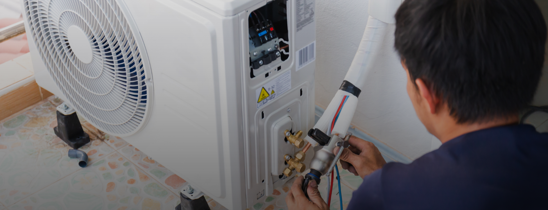 Technician connecting refrigerant lines to outdoor heat pump unit during installation