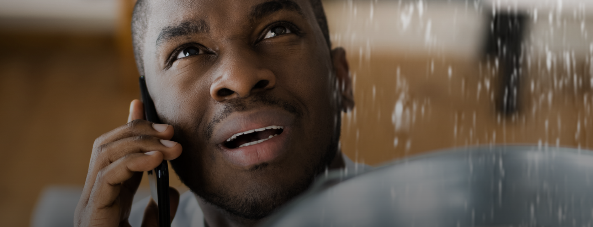 Homeowner calling plumber while dealing with leaking water inside home