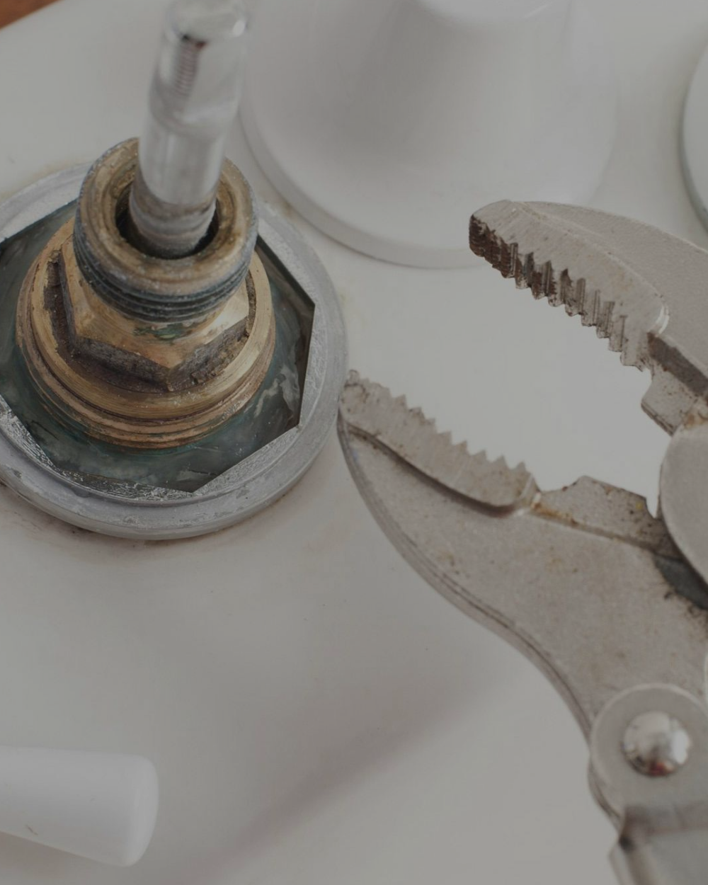 Close-up of a plumbing part with a wrench gripping a metal pipe fitting or valve.