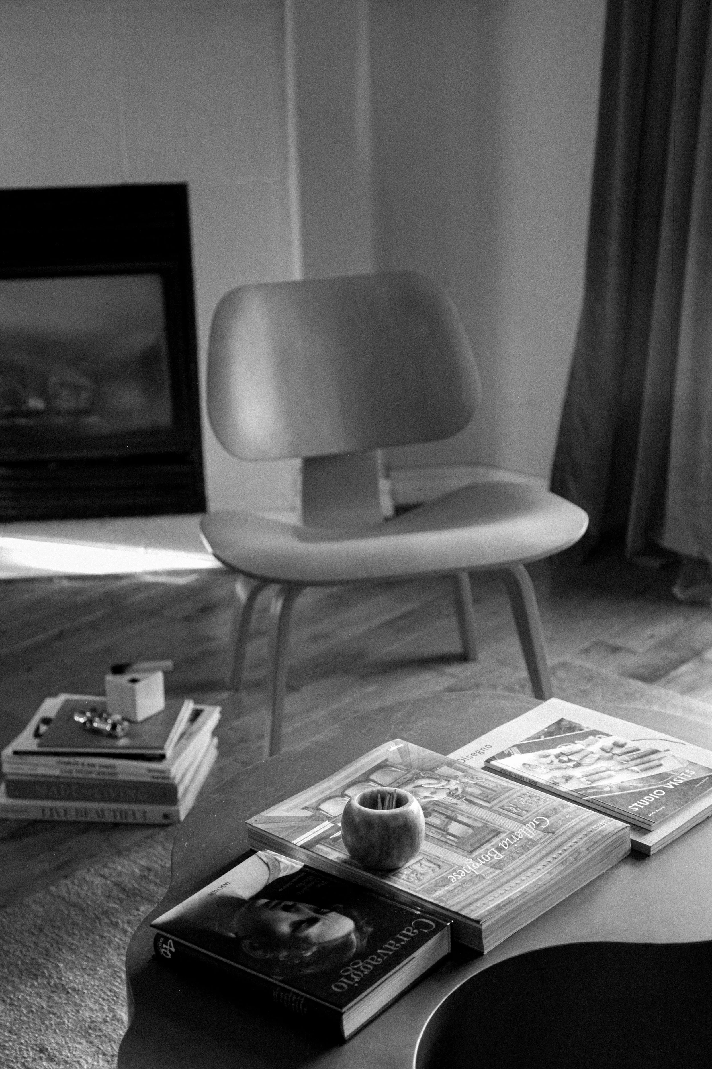 Close-up of an interior designer's hand styling books on a modern coffee table, showcasing a detailed residential interior design process and e-design curation.