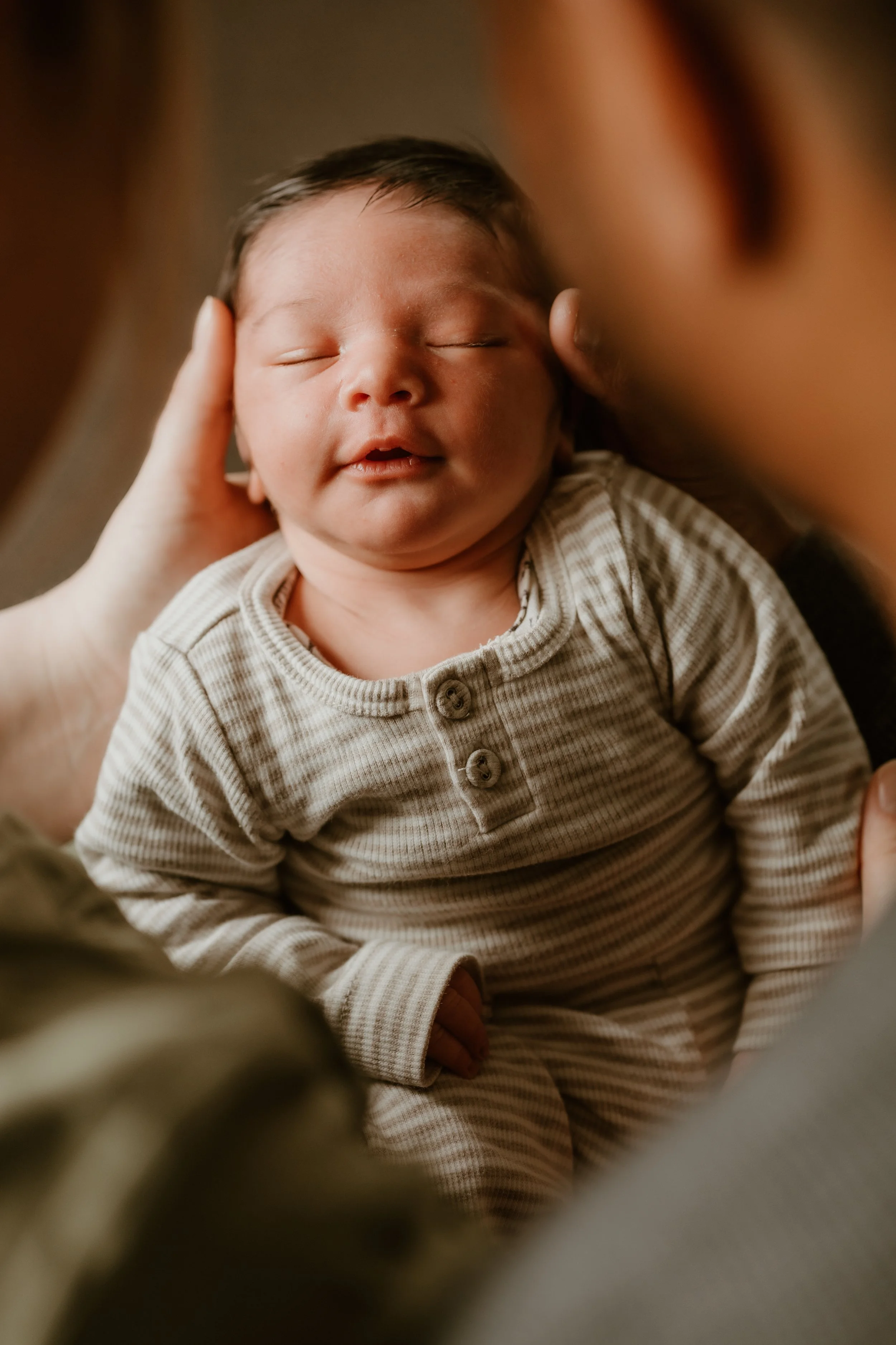 A happy family of four, including a mother, father, older sister, and a newborn baby, gathered closely together in a warm embrace, smiling and appearing loving.
