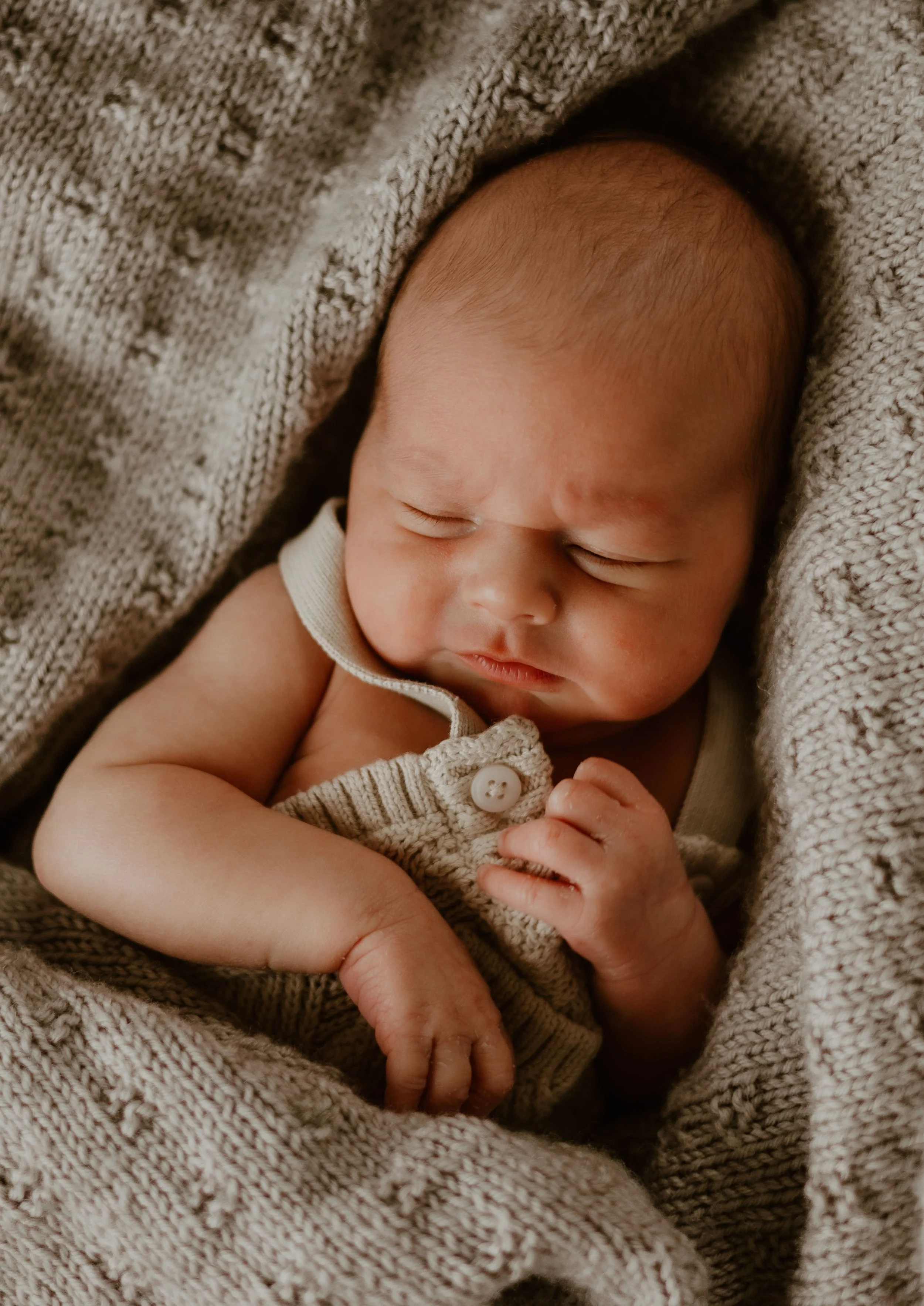 A sleeping baby wrapped in a cozy beige blanket.