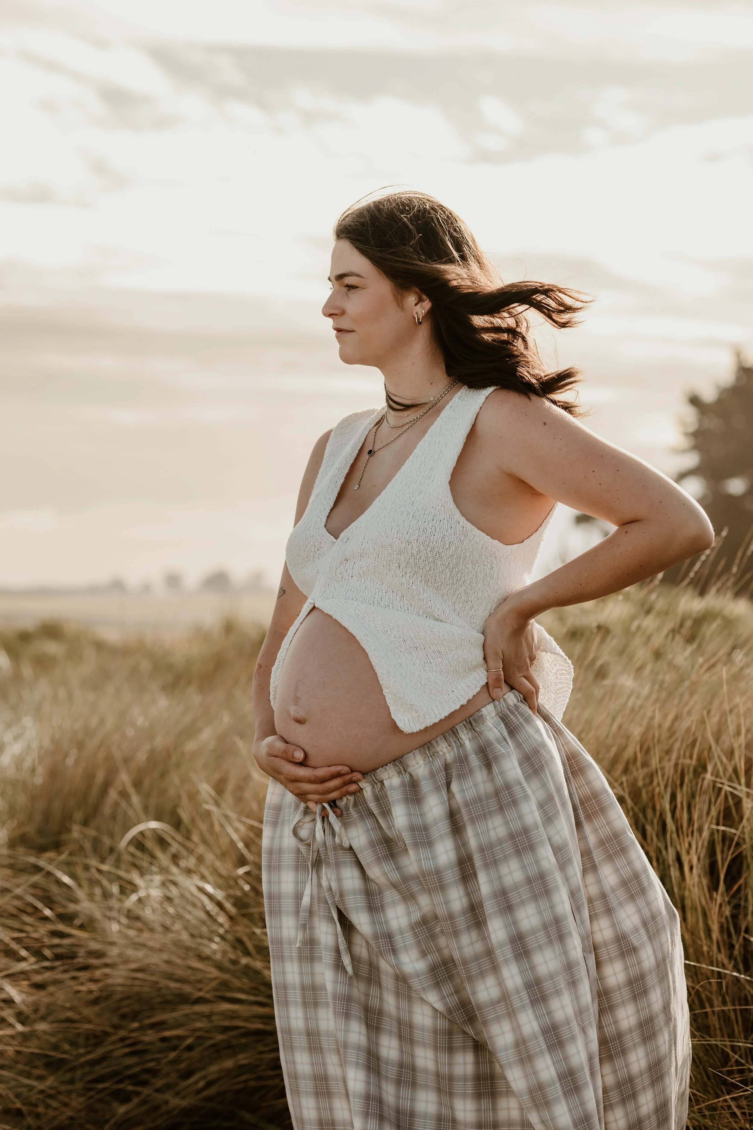 A man and woman with their faces close together, smiling and touching foreheads in an outdoor setting.