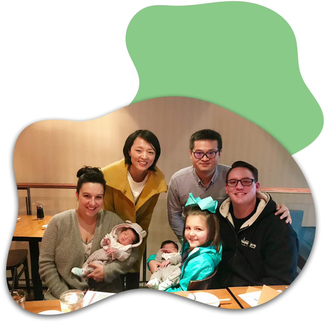 Family group photo at a restaurant with two infants and four adults, smiling for the camera.