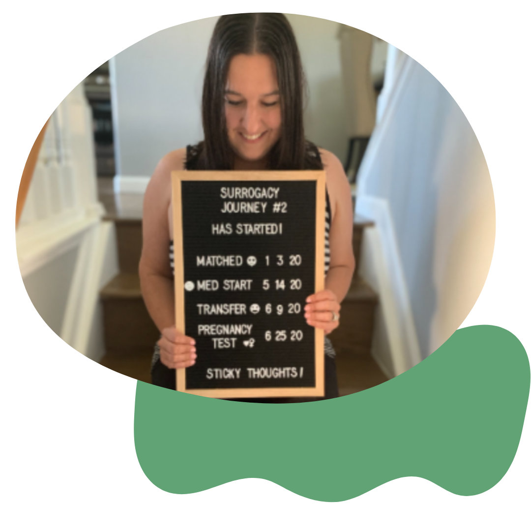 Woman holding a black letter board with updates about her surrogacy journey, including match, medical start, transfer, pregnancy test, and sticky thoughts.