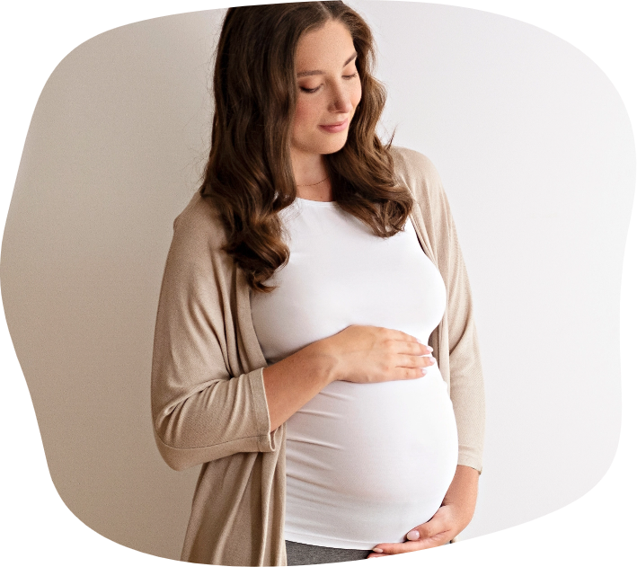 Pregnant woman gently touching her belly and smiling.