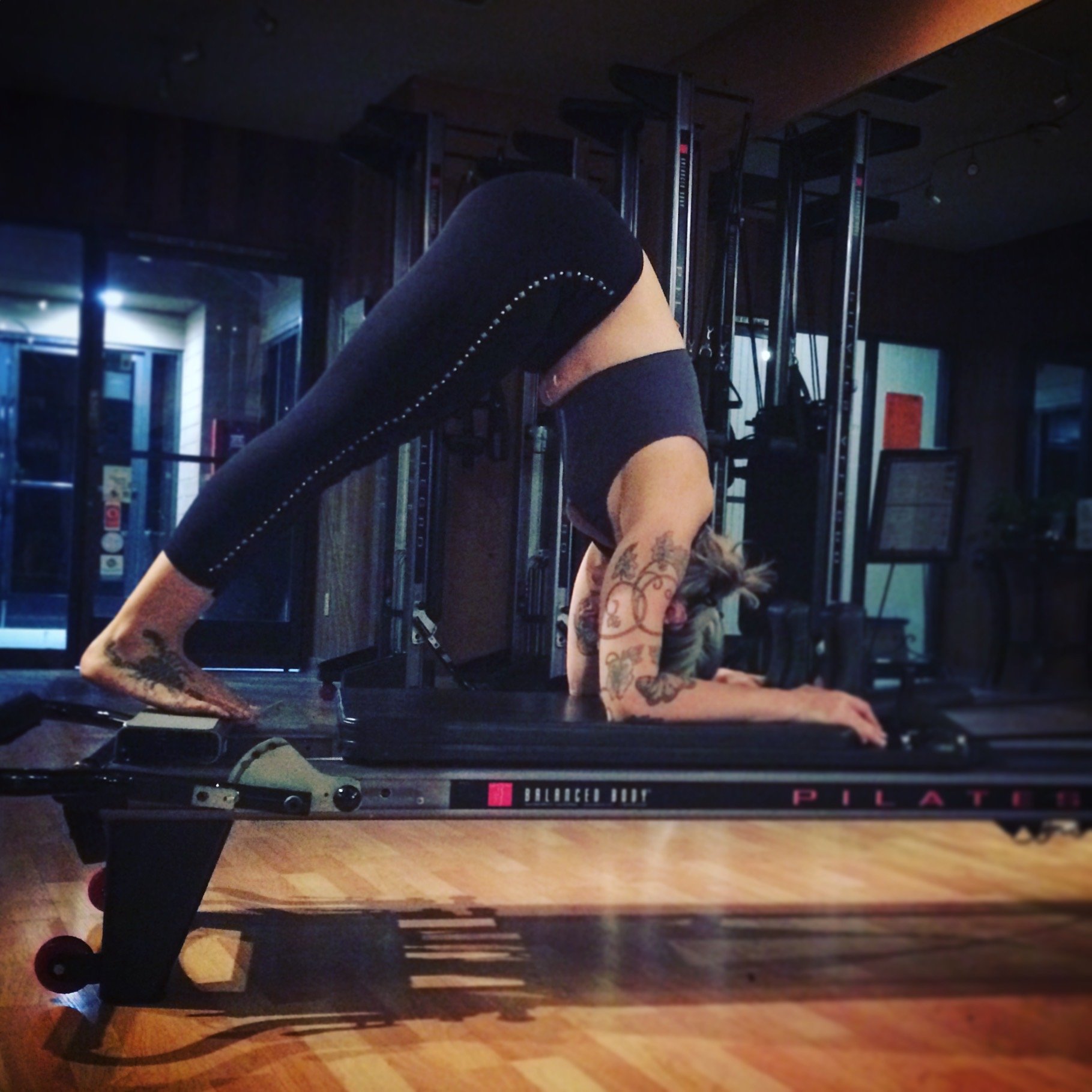 A woman doing a core pike exercise on a Pilates reformer