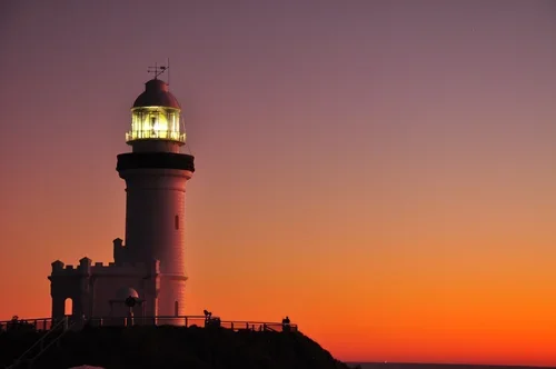 Lighthouse at sunset with a colorful sky.