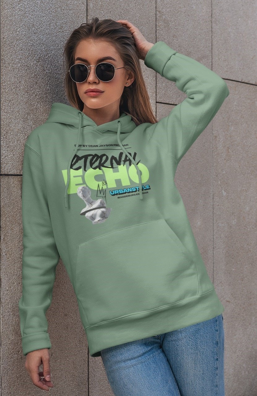 Junge Frau trägt eine grüne Kapuzenpullover mit graffiti-Design und blauen Jeans, trägt schwarze Sonnenbrille und lehnt an einer Steinmauer.
