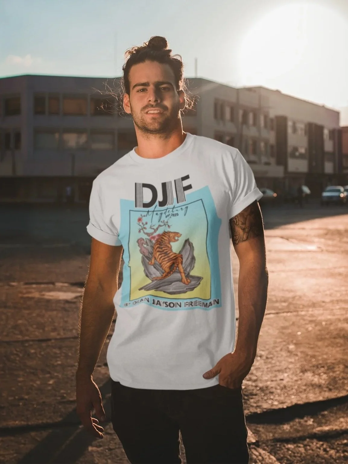 Ein junger Mann mit lockiger Haarmähne trägt ein weißes T-Shirt mit tigerförmigem Design und einem Dach im Hintergrund bei Sonnenuntergang in einer Stadt.