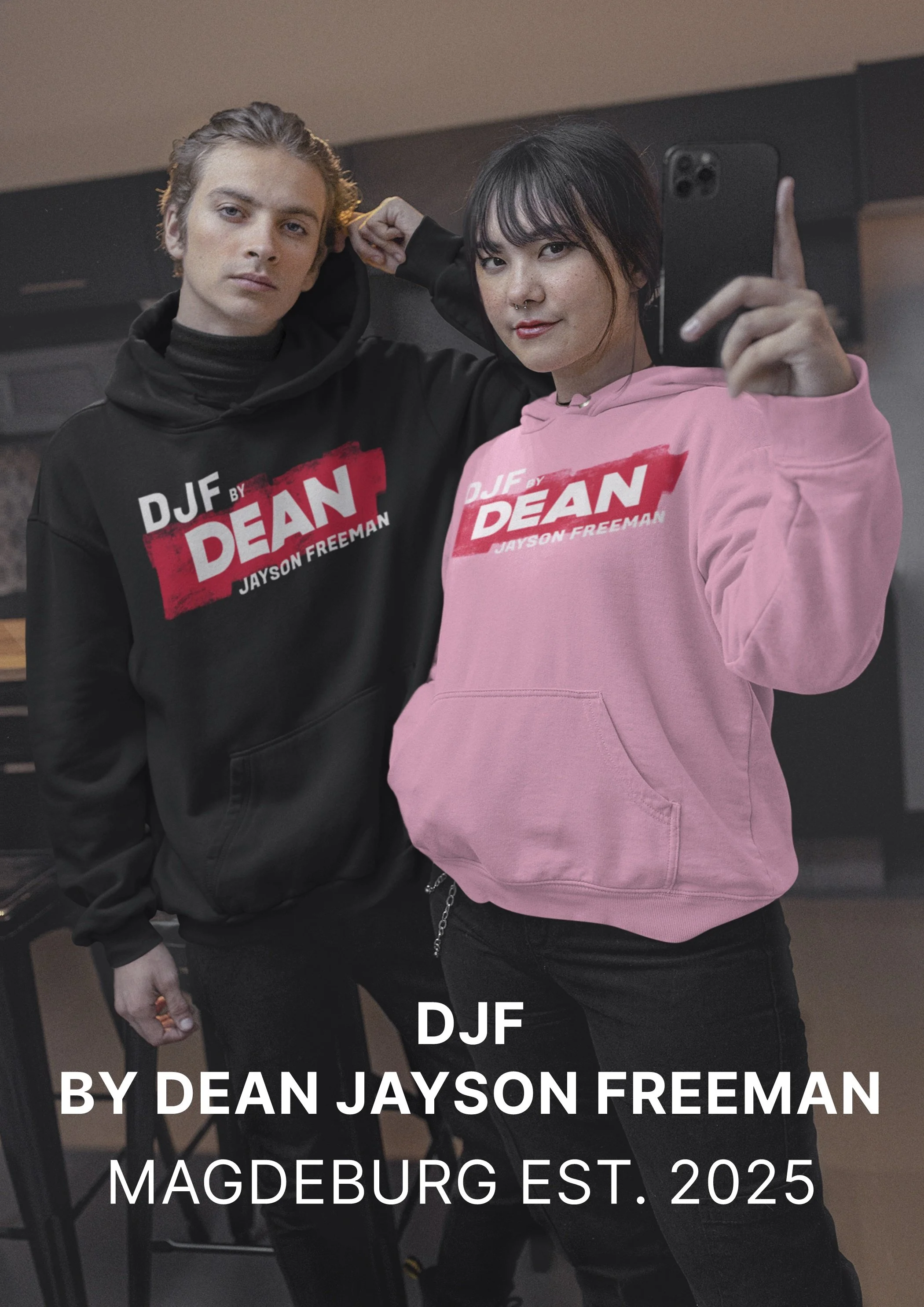 Zwei junge Menschen, ein Mann mit blonden Haaren und ein Mädchen mit schwarzen Haaren, nehmen ein Selfie auf. Beide tragen Hoodies mit dem Text 'DJF by Dean Jayson Freeman'.