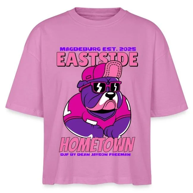 Ein rosa T-Shirt mit einem cartoonartigen Hund in einer durchsichtigen Sonnenbrille und einem Baseballkappen, mit Texten wie 'Magdeburg Est. 2025', 'Eastside', 'Hometown' und 'D.J.F by Dean Jayson Freeman'.