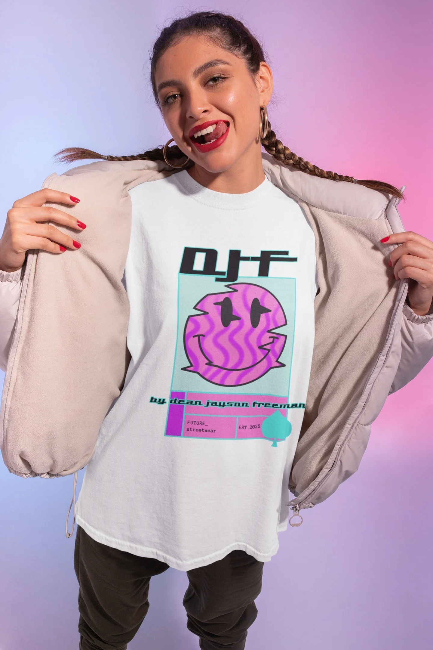 Junge Frau trägt weißen T-Shirt mit lachendem lila Smiley-Gesicht und Text, geöffnetes beige Jackett, lächelt und zeigt die Zunge, im Hintergrund mit Farbverlauf von Blau zu Pink.