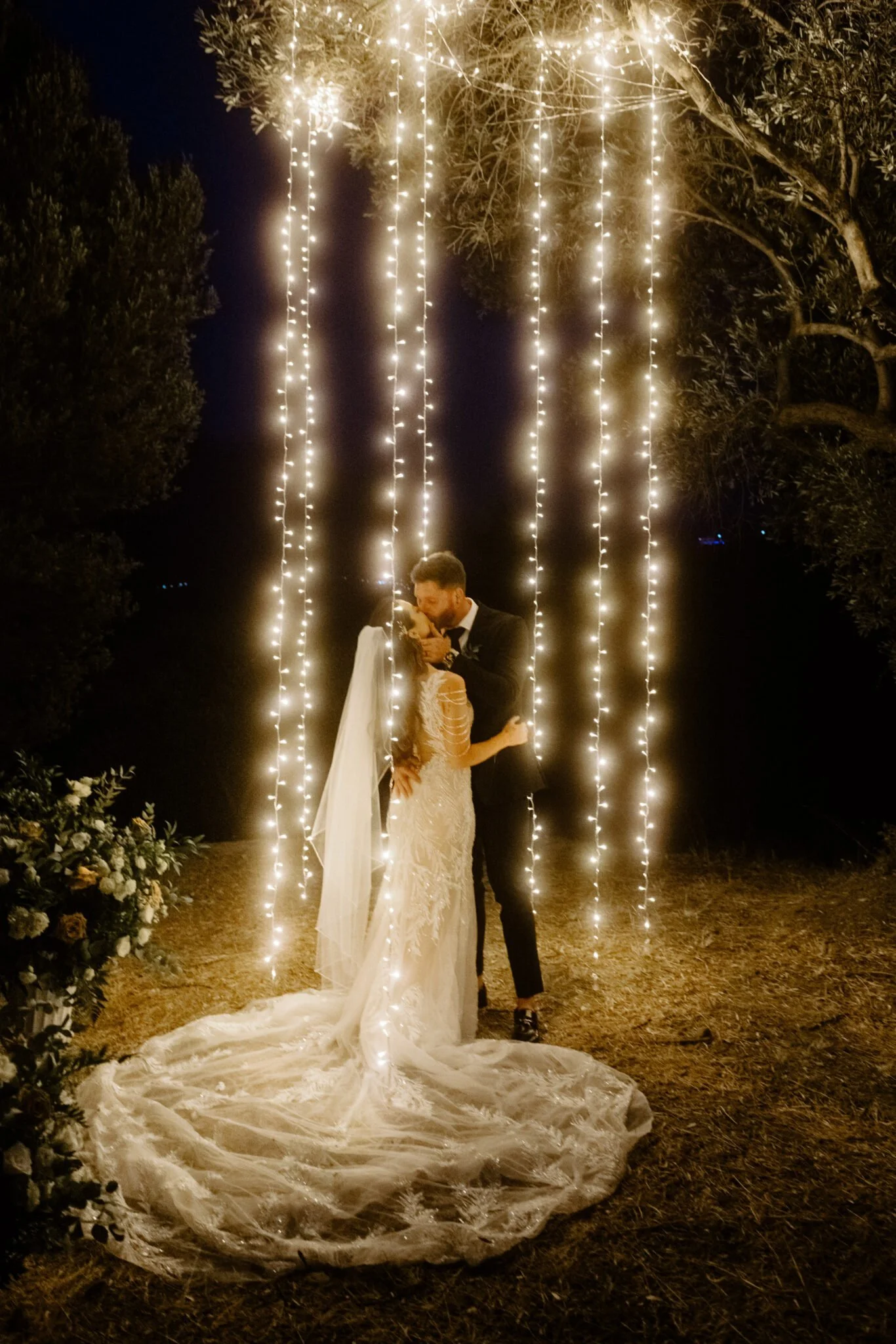 a couple giving a kiss at the fairy light garland elopement crete