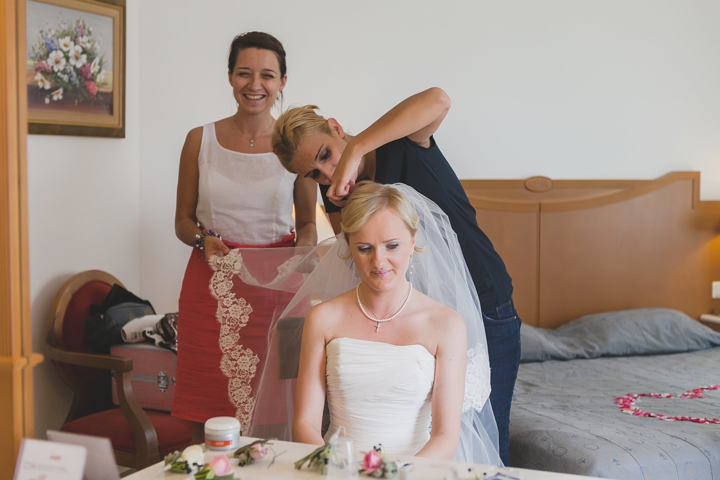 wedding planner assisiting to a bridal stylist to put a vaile for a bride