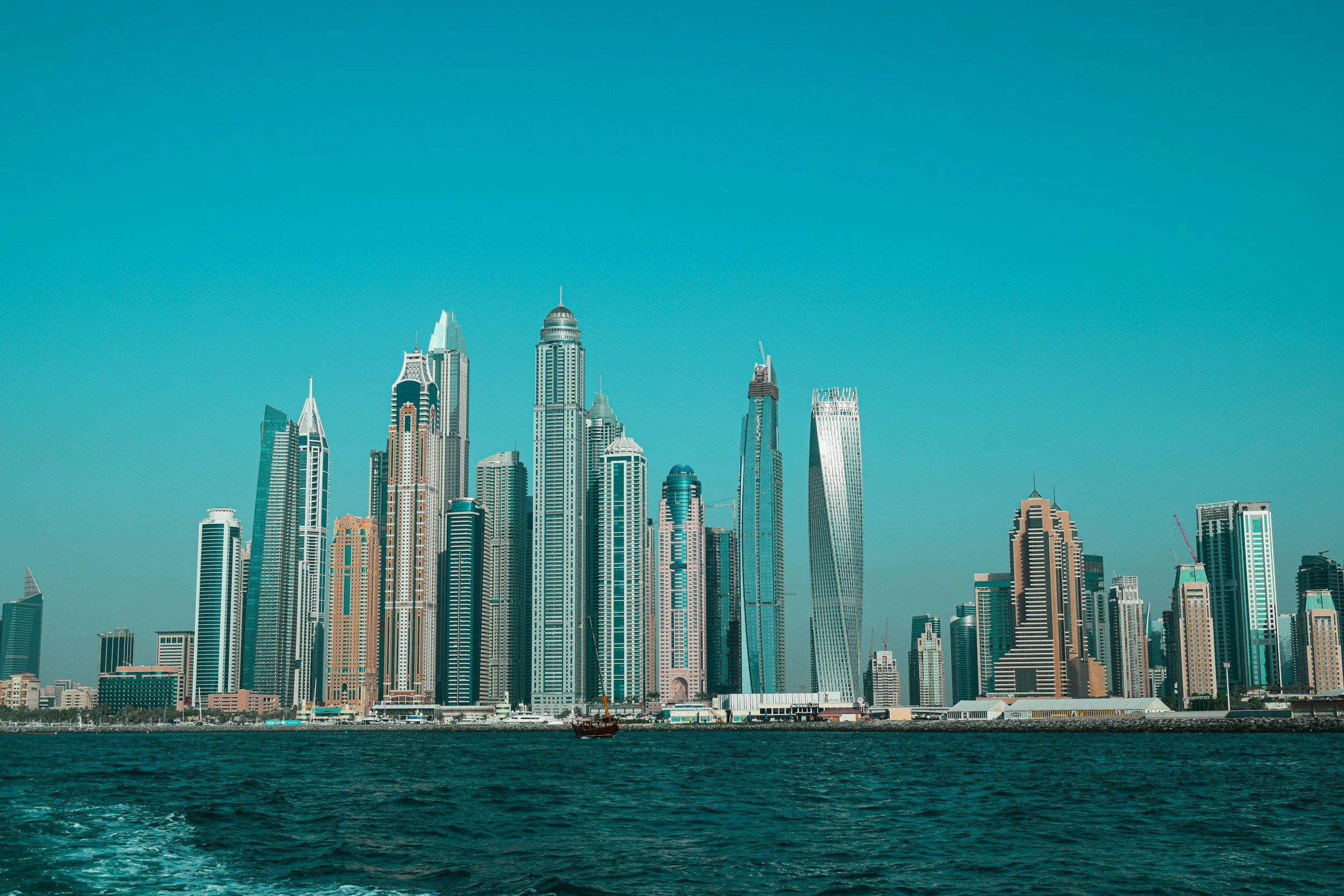 Dubai skyline with modern skyscrapers along the waterfront under a clear blue sky.