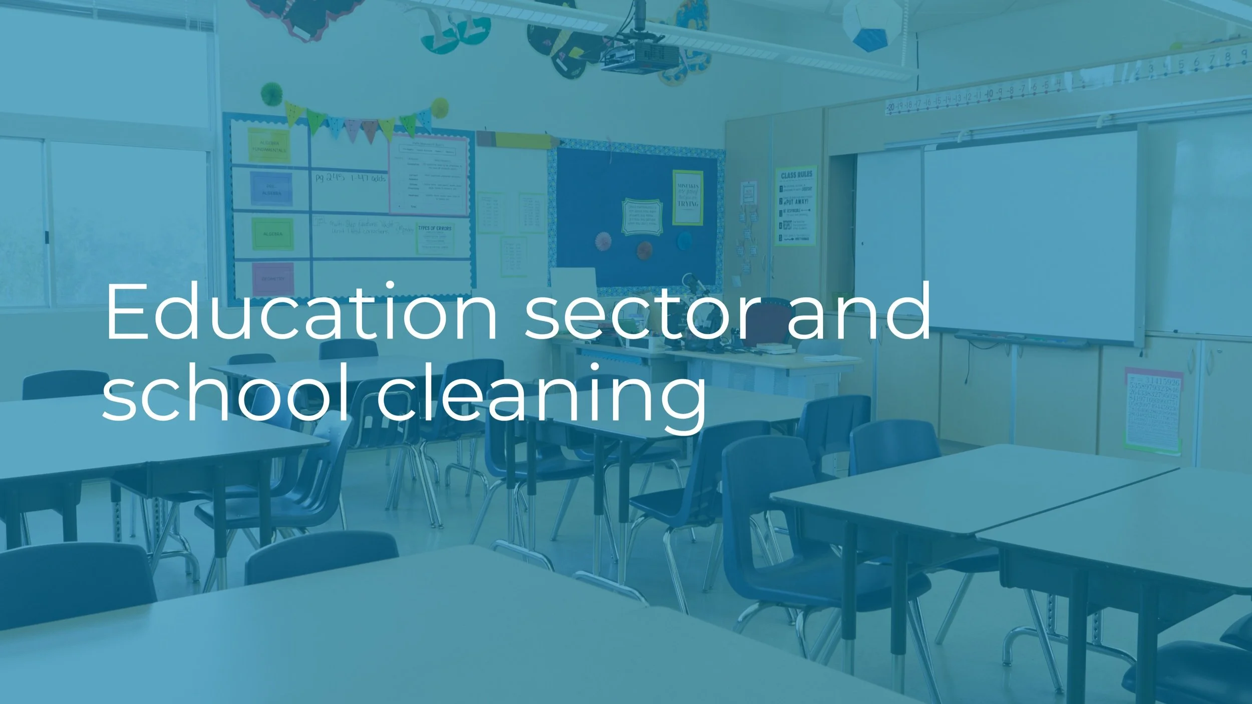 Empty classroom with tables, chairs, whiteboard, and posters on the walls, with a window showing a cloudy sky outside.