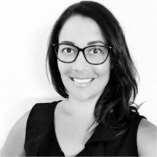 A woman with glasses and shoulder-length dark hair, smiling at the camera, in black and white.
