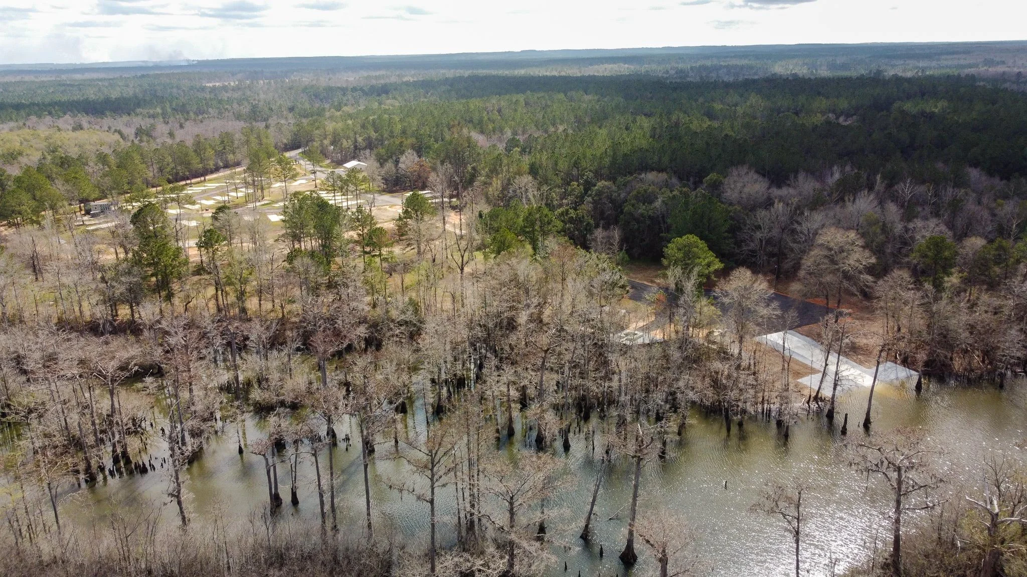 Aerial view of Escambia River and surrounding forest near Chumuckla Springs RV Resort in Northwest Florida with RV sites visible among trees