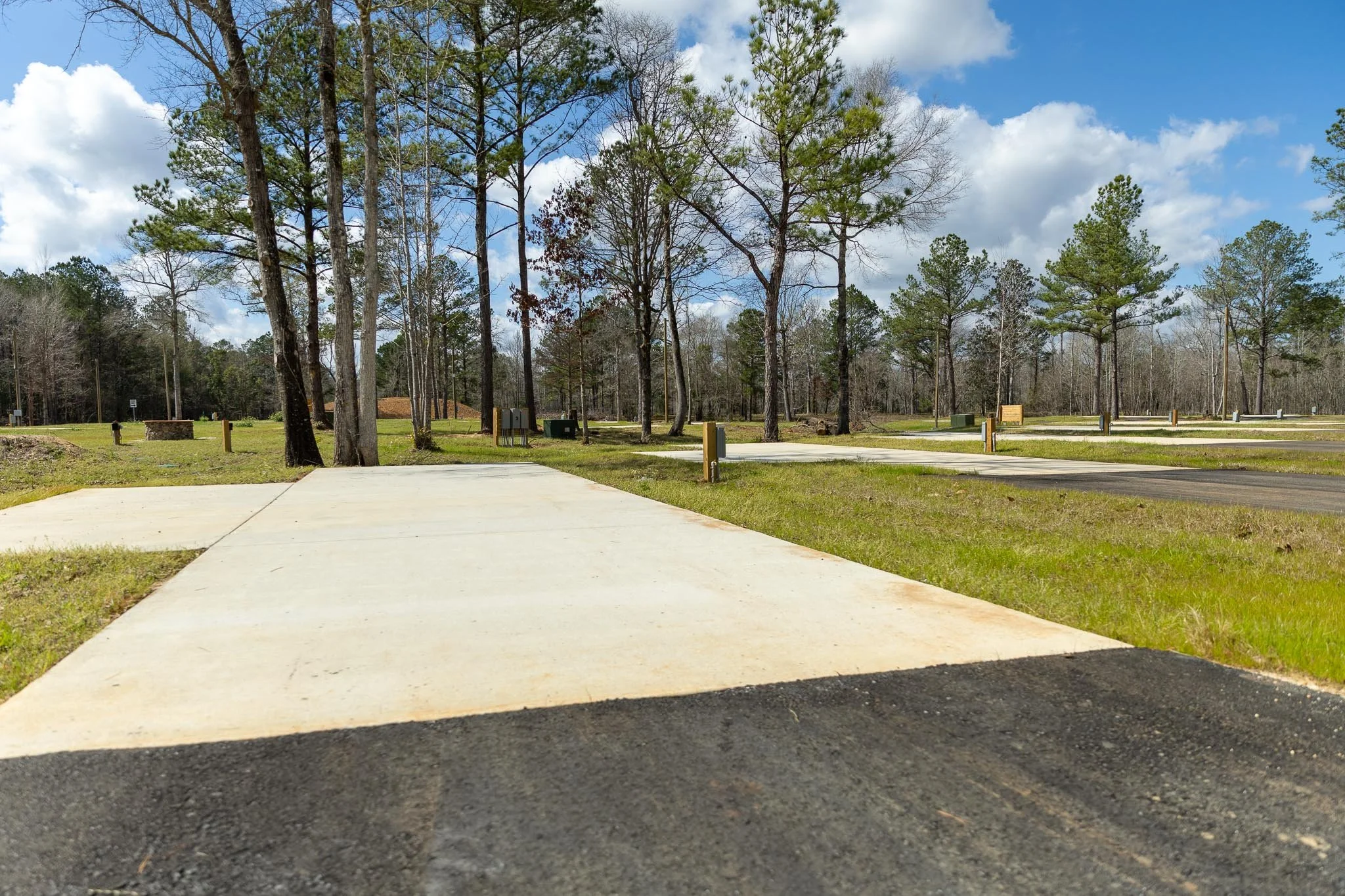 A person working at a desk with a laptop, smartphone, notebook, pen, a camera, sunglasses, a wooden clock, a globe, and a model airplane.