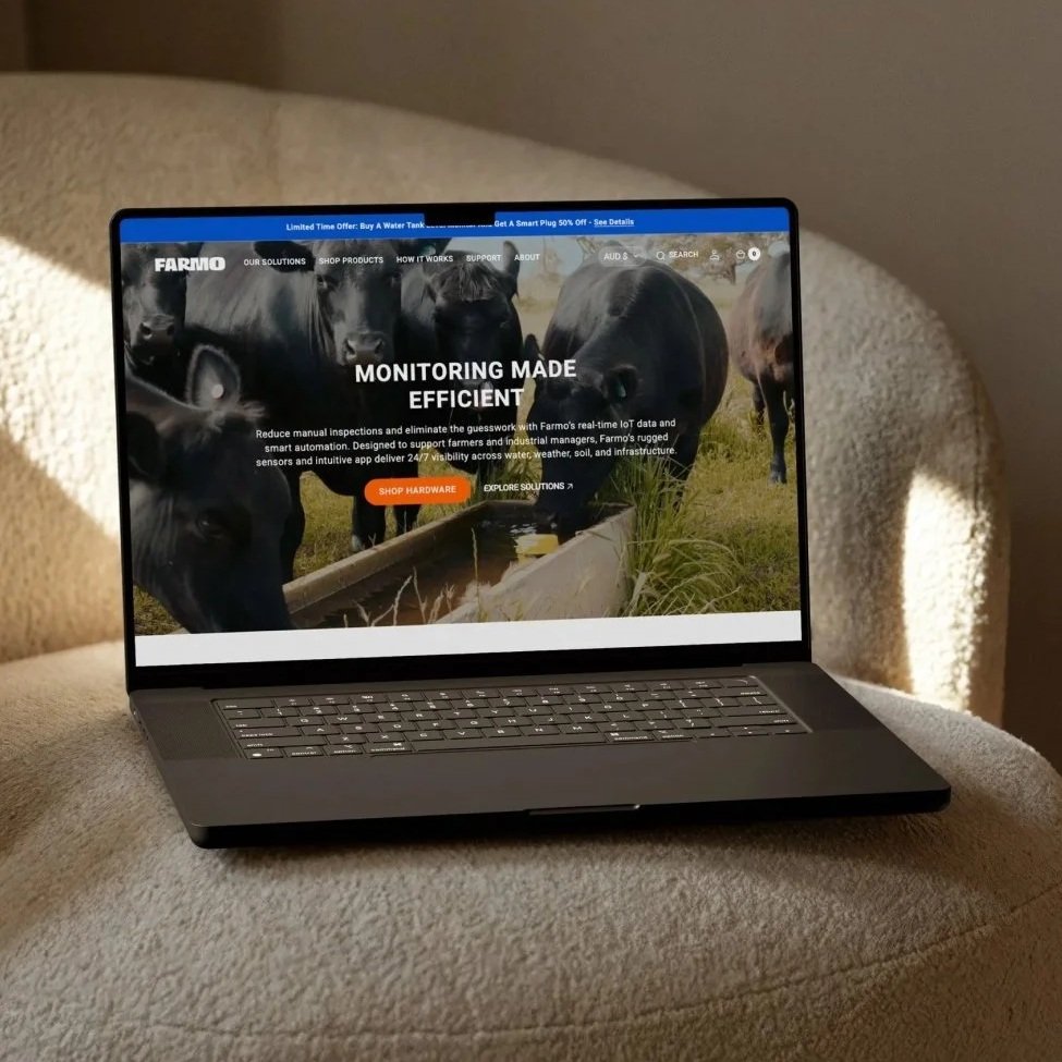 Laptop on a beige armchair displaying Farmo's website about monitoring systems for farms.
