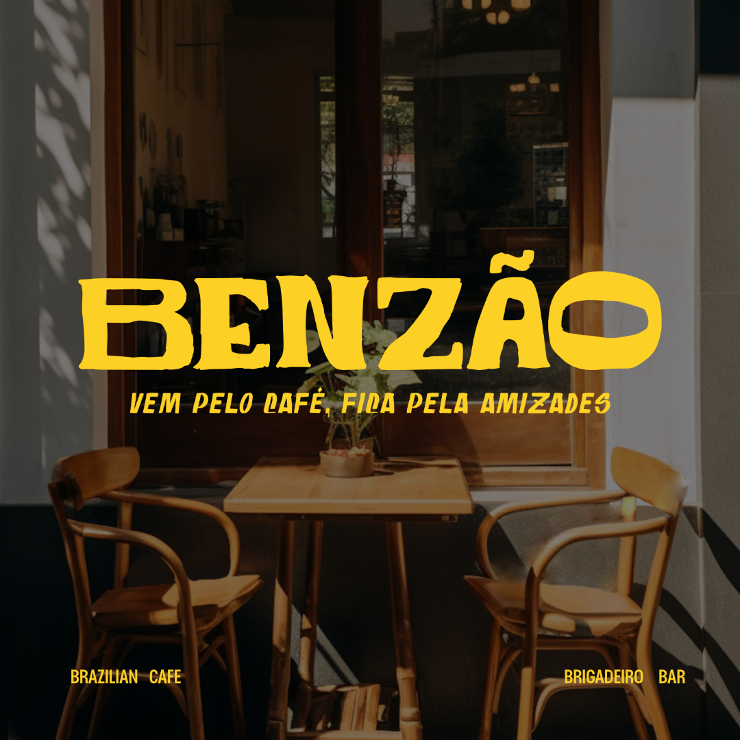 A cozy cafe with wooden furniture and a window showing outdoor greenery. Overlaid text reads 'BENZÃO' in large yellow letters, with smaller yellow text saying 'VEM PELO CAFÉ, FILA PELA AMIZADES'. Additional small yellow text at the bottom left says '
