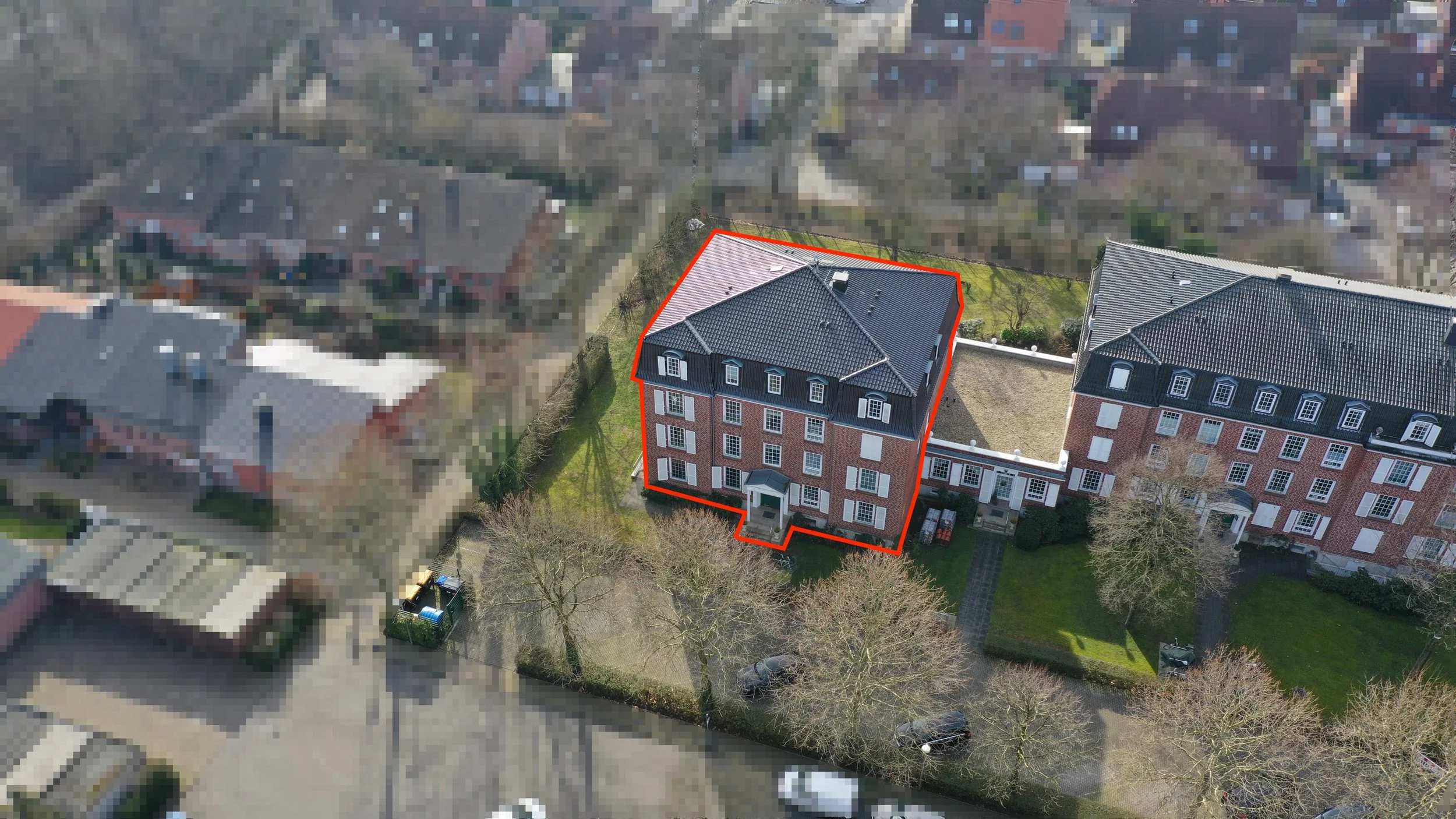 Luftaufnahme eines Gebäudes innerhalb eines umzäunten Gartens, umgeben von anderen Gebäuden in einem Wohngebiet.