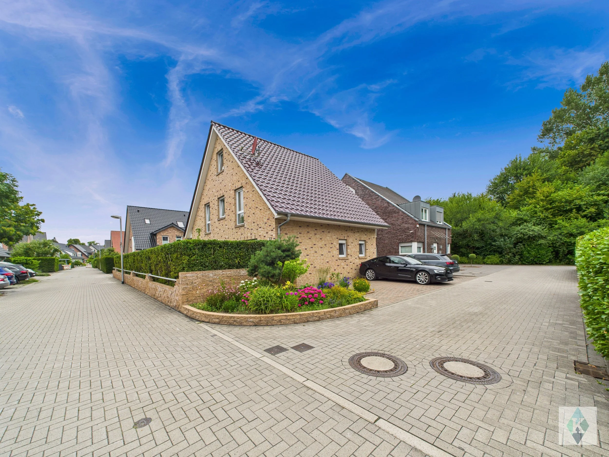 Ein modernem Wohngebiet mit mehrstöckigen Häusern, einem Parkplatz und einer gepflegten Gartenanlage unter einem blauen Himmel.