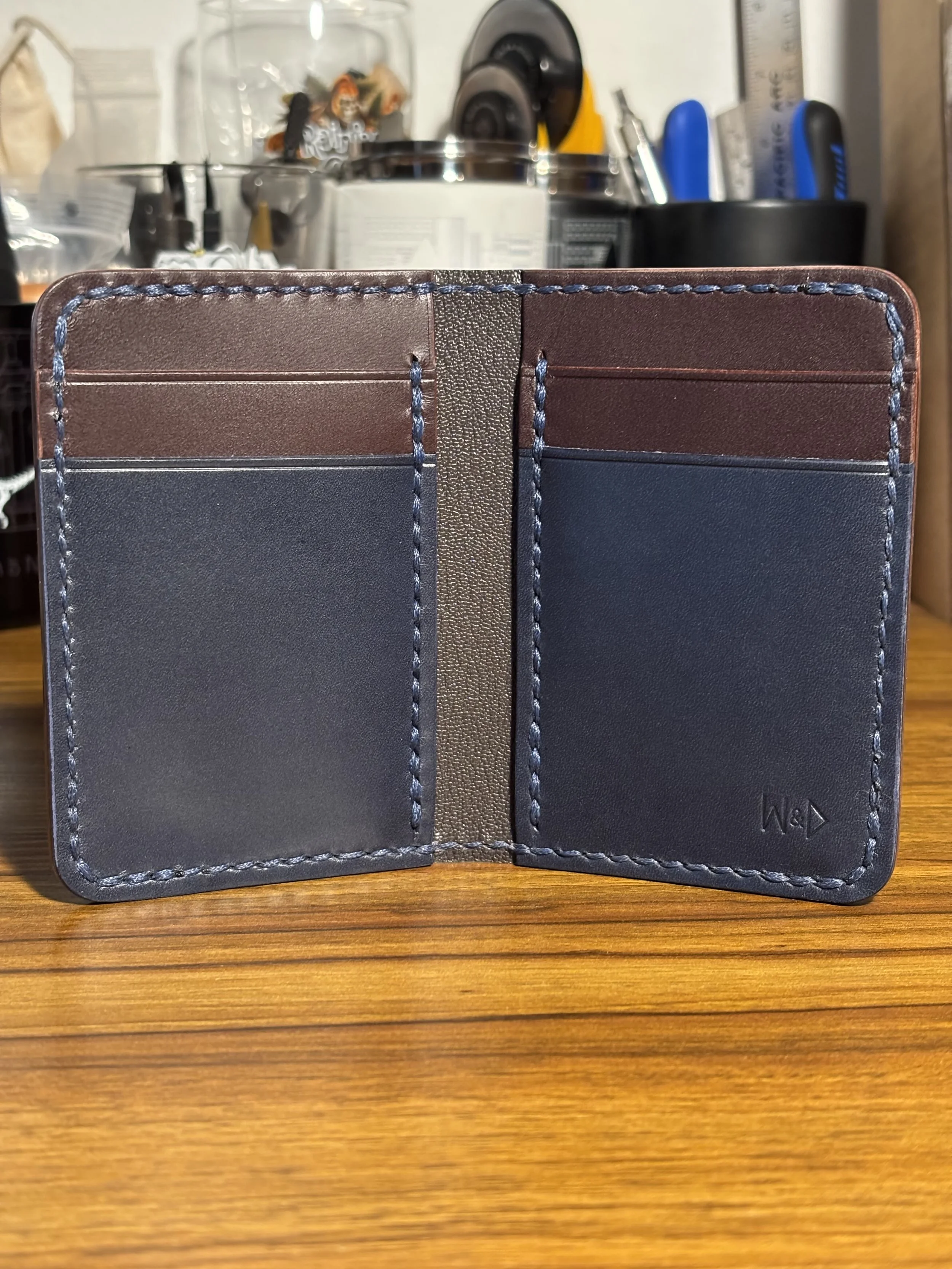The Kraken handmade navy blue and brown leather bifold wallet showing four interior card pockets and saddle stitching